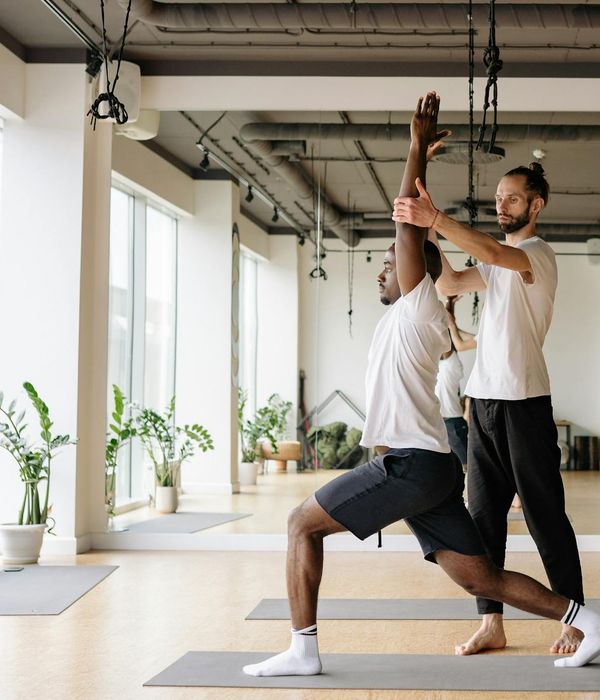 Man performing a controlled stretching exercise in a minimalist gym.